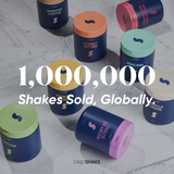 Assorted containers with colorful lids on a marble surface, featuring Daily Shake branding.